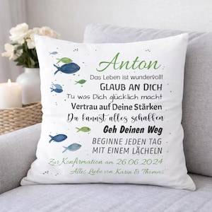May include: A white square throw pillow featuring a printed design of small blue and green fish. The text reads: Anton, Das Leben ist wundervoll! GLAUB AN DICH, Tu was Dich gl&uuml;cklich macht, Vertrau auf Deine St&auml;rken, Du kannst alles schaffen, Geh Deinen Weg, BEGINNE JEDEN TAG MIT EINEM L&Auml;CHELN, Zur Konfirmation am 26.06.2024, Alles Liebe von Karin & Thomas.