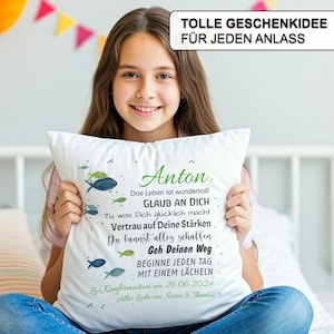 May include: A white square throw pillow featuring a printed design of small blue and green fish. The text reads: Anton, Das Leben ist wundervoll!, GLAUB AN DICH, Tu was Dich gl&uuml;cklich macht, Vertrau auf Deine St&auml;rken, Du kannst alles schaffen, Geh Deinen Weg, BEGINNE JEDEN TAG MIT EINEM L&Auml;CHELN, Zur Konfirmation am 26.06.2024, Alles Liebe von Karin & Thomas.