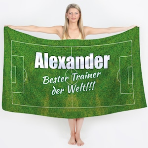 Może przedstawiać: Zielony ręcznik plażowy z wzorem boiska piłkarskiego. Ręcznik ma nadrukowany tekst "Alexander Bester Trainer der Welt!!!".