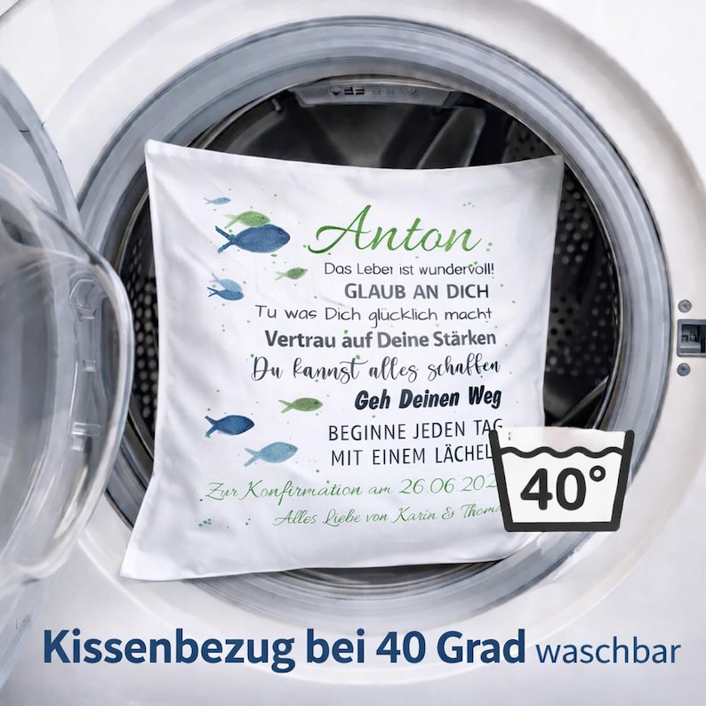 May include: A white square pillowcase featuring blue and green fish illustrations and German text including the name Anton, inspirational quotes, and a confirmation date. A black and white icon indicates the fabric is machine washable at 40 degrees.