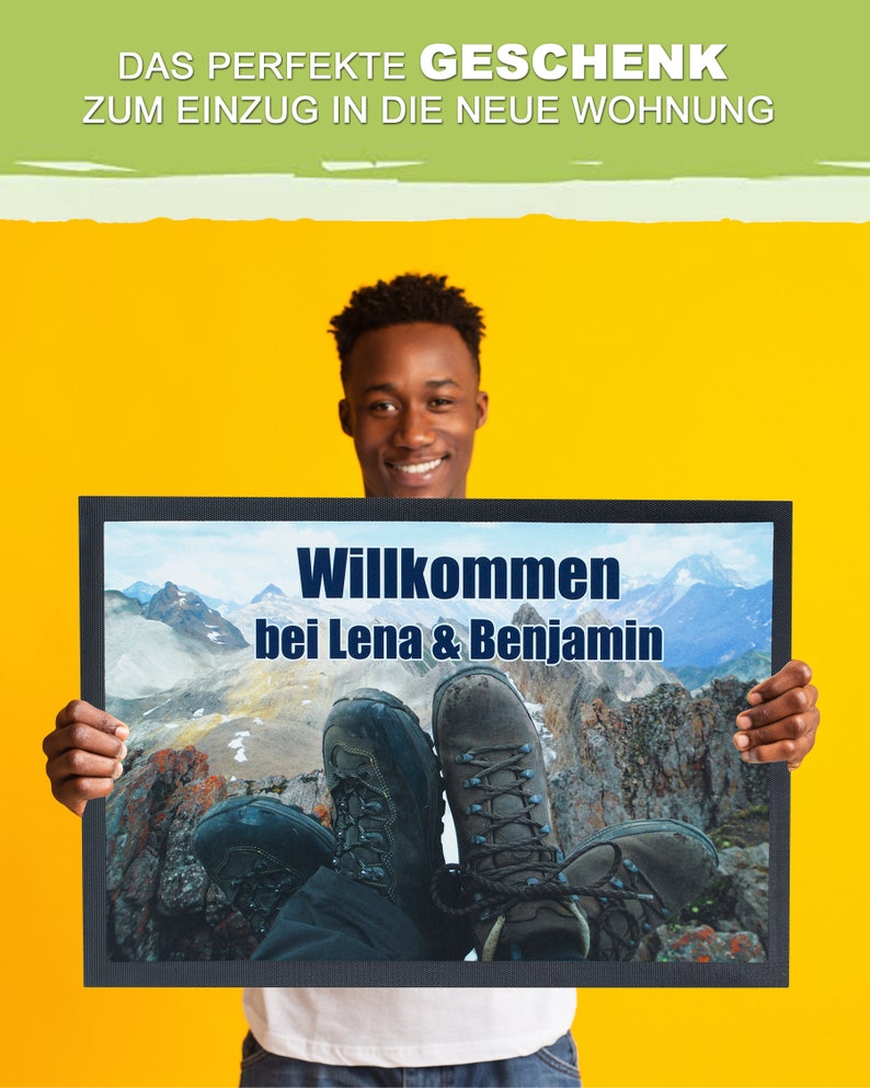 May include: A person holds a welcome mat with a mountain scene and the text "Willkommen bei Lena & Benjamin".