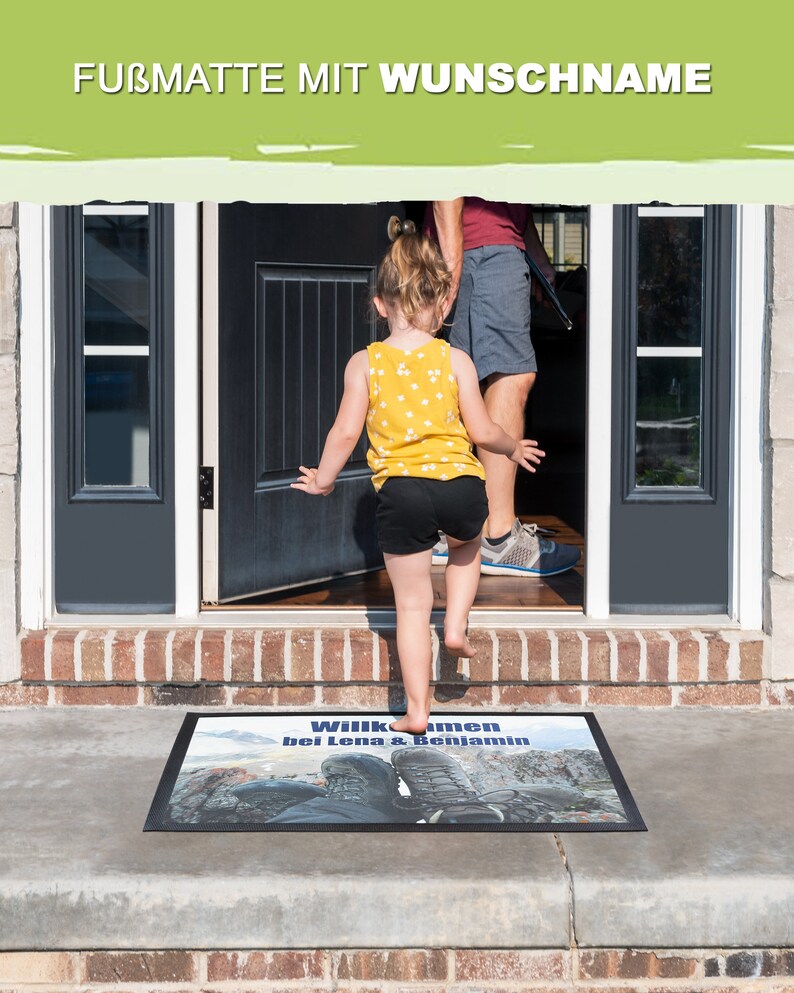May include: A welcome mat with the text "Willkommen bei Lena & Benjamin" printed on it. The mat is black with a blue and white image of hiking boots on a mountain path.