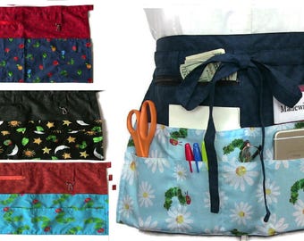 Peut inclure: Tabliers de taille avec différents motifs. Un tablier présente un motif de marguerites et de chenilles bleu et blanc. D'autres tabliers ont des tissus rouges, noirs et bleus avec des motifs floraux et célestes. Chaque tablier a plusieurs poches.