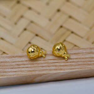 May include: A pair of gold ladybug earrings. The earrings are small and delicate, with a detailed design.