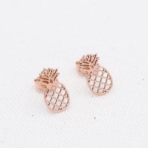 Könnte beinhalten: Ein Paar Ohrringe in Roségold in Form von Ananas. Die Ohrringe sind aus Metall und haben ein filigranes, ausgeschnittenes Design.