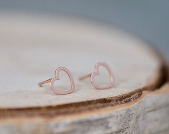 Puede incluir: Un par de pendientes de corazón de oro rosa. Los pendientes son simples y delicados, con un diseño de corazón hueco.