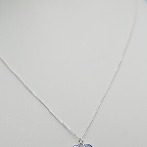 May include: A silver necklace with a heart-shaped pendant featuring a detailed angel wing design.