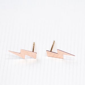 Peut inclure: Une paire de boucles d'oreilles clous en or rose en forme d'éclair.