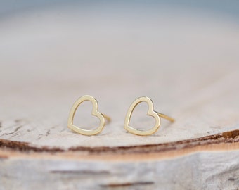 Puede incluir: Un par de pendientes de botón de corazón de oro. Los pendientes son simples y delicados, con un diseño de corazón hueco.