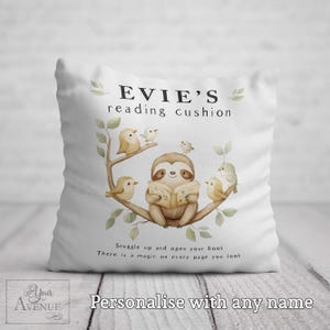 May include: White square cushion with a watercolour illustration of a sloth reading a book, surrounded by birds on a branch. Text reads "EVIE'S reading cushion" and "Snuggle up and open your book".
