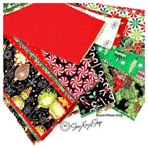 May include: A collection of rectangular fabric pieces featuring various Christmas-themed patterns including red polka dots, peppermint swirls, green holly, pine branches, and colorful ornaments on black backgrounds. Text reads Stock Photo Only.
