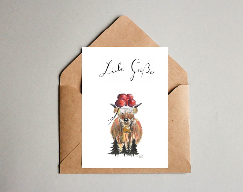 May include: A greeting card with a watercolor illustration of a brown and white cow wearing a red berry crown. The cow is standing in a forest with green trees. The text "Liebe Gr&uuml;&szlig;e" is written in black cursive at the top of the card.