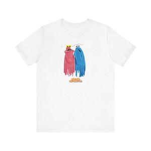 Puede incluir: Camiseta blanca con un gráfico de dos personajes de dibujos animados, uno rosa y otro azul, con el texto "Keep it weird and funky, ok?"