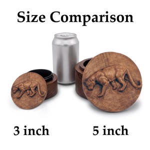 May include: Two round wooden containers with lids featuring a carved mountain lion design. The smaller container is labeled 3 inch and the larger container is labeled 5 inch. A silver aluminum beverage can is placed between them for size comparison.