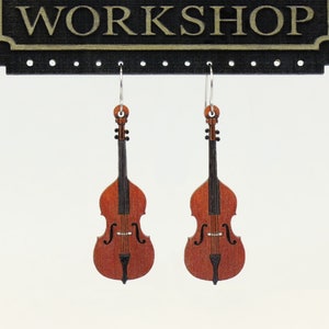 May include: A pair of wooden earrings shaped like double basses. The earrings are brown with black details and are hanging from silver hooks.