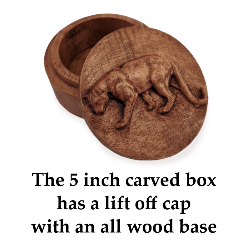 May include: A round brown wooden box measuring 5 inches in diameter with a lift-off lid. The lid features a detailed relief carving of a prowling panther. The text below reads: The 5 inch carved box has a lift off cap with an all wood base.