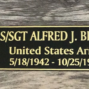 May include: A black nameplate with gold trim and text. It features the text "S/SGT ALFRED J. BRION", "United States Army", and dates 5/18/1942 - 10/25/1945. An American flag and a United States Army emblem are on the left.