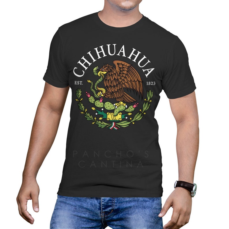 May include: Black t-shirt with a white graphic of the Mexican coat of arms, featuring an eagle with a snake in its beak, surrounded by a wreath of cactus plants. The text "CHIHUAHUA EST. 1823" is above the graphic, and "PANCHO'S CANTINA" is below.