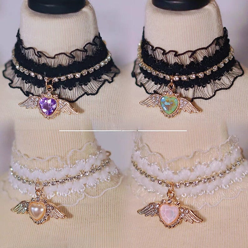 May include: Four delicate choker necklaces with a heart pendant and wings. Two are black lace with rhinestones and two are white lace with rhinestones. The heart pendants are purple, green, white, and pink.