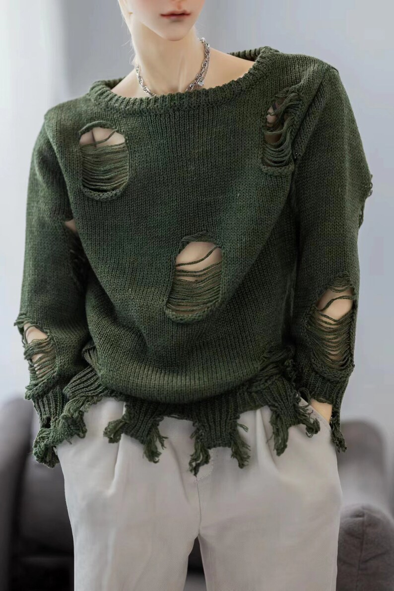 May include: A dark green sweater with distressed detailing and frayed edges. The sweater has several large holes throughout.
