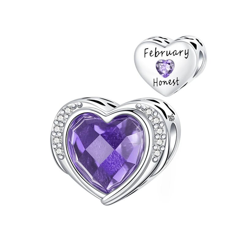 May include: A silver heart-shaped charm with a large, faceted purple gemstone center. The charm is accented with small clear crystals around the edge. A smaller heart charm with the words "February" and "Honest" is also shown.