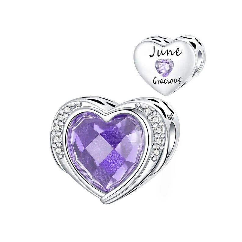 May include: A heart-shaped charm with a large, faceted purple gemstone center, surrounded by a silver frame and small clear crystals. A smaller charm with the text "June Gracious" and a purple gemstone is also shown.