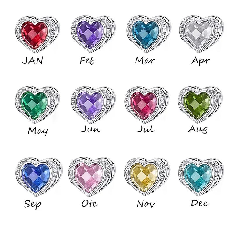 May include: A collection of heart-shaped charms, each with a different colored gemstone and a silver-colored border. Each charm has a month of the year labeled on it: Jan, Feb, Mar, Apr, May, Jun, Jul, Aug, Sep, Oct, Nov, and Dec.