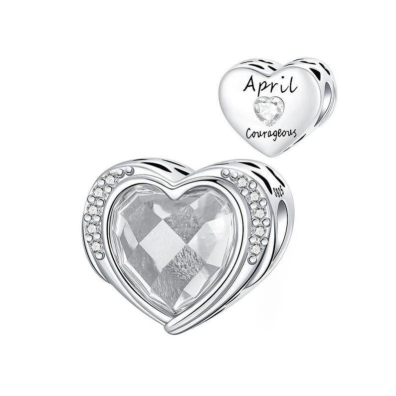 May include: A silver heart-shaped charm with a large, faceted clear crystal center, surrounded by a row of small clear crystals. A smaller heart charm with the word "April" and "Courageous" is also shown.