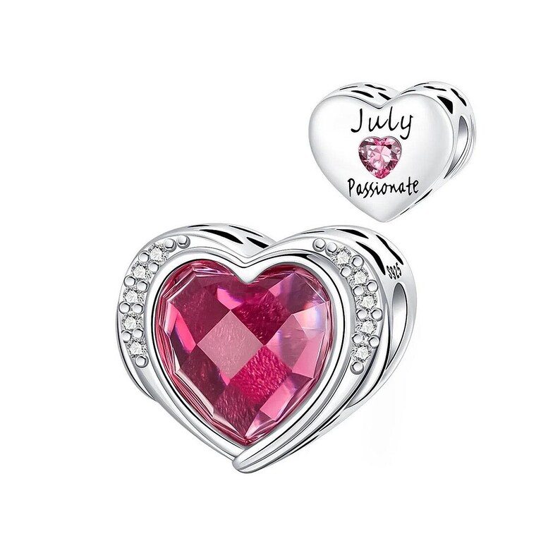 May include: A silver heart-shaped charm with a large, faceted pink gemstone center. The charm is accented with small, clear crystals around the edge. A smaller heart charm with the word "July" and "Passionate" is also shown.
