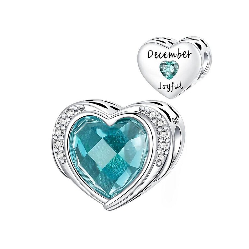 May include: A silver heart-shaped charm with a large, faceted teal gemstone center, surrounded by small clear crystals. A smaller heart charm with the words "December" and "Joyful" and a teal gemstone is also shown.