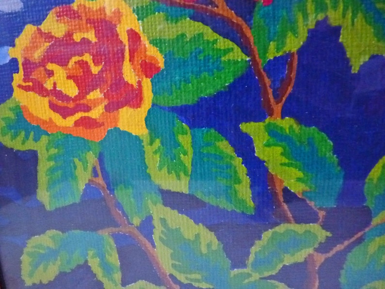 May include: A close-up of a painting depicting a single yellow rose with red accents, surrounded by green leaves on a dark blue background.