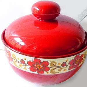 May include: Red ceramic bowl with a lid and floral design. The bowl has a white band with red flowers and gold accents.
