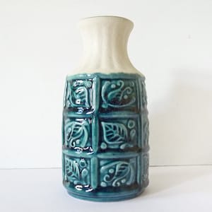 Può includere: Un vaso in ceramica blu e bianco con un motivo geometrico di foglie e volute. Il vaso ha un collo stretto e una base larga.