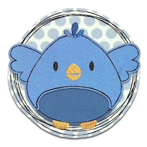 May include: A blue bird with a yellow beak and black eyes is embroidered on a white background with gray polka dots. The bird is surrounded by a black circle with a white outline.