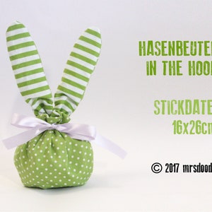 May include: Green fabric bunny bag with white stripes and polka dots. The bag is tied with a white ribbon. The text "HASENBEUTEL IN THE HOOP STICKDATEI 16x26cm © 2017 mrsdoodle" is printed on a white background.