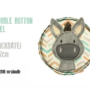 May include: A gray donkey face embroidered on a round fabric patch with a chevron pattern in shades of teal, orange, and white. The patch is surrounded by a black stitched circle. The text "DOODLE BUTTON ESEL STICKDATEI 7x7cm © 2016 mrsdoodle" is printed below the patch.