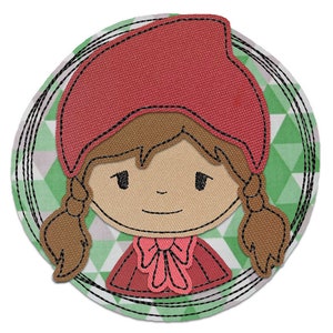 Può includere: Una bambina con cappuccio rosso, capelli castani e un fiocco rosso. La bambina è circondata da un motivo geometrico verde e bianco.