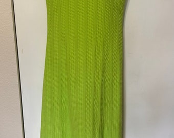 Puede incluir: Un vestido verde lima sin mangas con un escote de cuentas blancas. El vestido tiene una tela texturizada y una silueta ajustada.