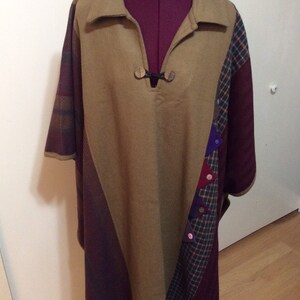May include: A brown, tan, and burgundy patchwork poncho with a collar and a button closure at the neck. The poncho has a variety of colorful fabric patches sewn on the front.