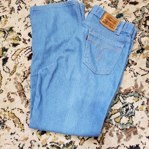 May include: A pair of light blue denim jeans with a brown leather Levi Strauss & Co. patch on the back waistband.