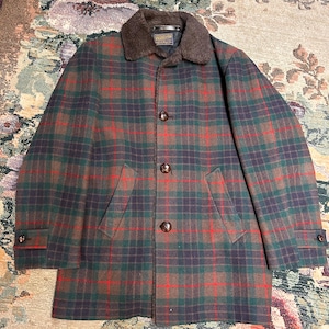 May include: A Pendleton wool coat featuring a dark green, brown, and red plaid pattern. The coat has a brown faux fur collar, three large brown buttons down the front, two side pockets, and buttoned cuffs on the long sleeves. A Pendleton label is visible.