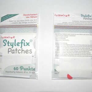 Könnte beinhalten: Eine Packung Stylefix Patches, ein Nähprodukt, das hilft, Stoffe vor dem Nähen zu fixieren. Die Packung enthält 60 Klebepunkte, jeder mit einem Durchmesser von etwa 30 mm. Die Packung ist weiß mit grünen und roten Akzenten und trägt den Text "Stylefix Patches" und "60 Punkte".