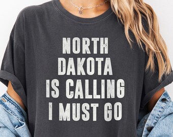 ノースダコタが呼んでいる！行かなきゃ！シャツ | トラベルTシャツ、ノースダコタへの移住者、冒険家、旅行好きの方へのギフト、心地よい色彩