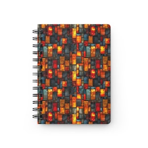 May include: Spiral-bound notebook featuring a vibrant, abstract pattern. The cover design showcases a mosaic of rectangular shapes in shades of red, orange, blue, and gray. The notebook's spiral binding is black.