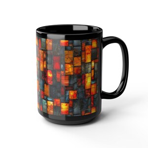 May include: Black ceramic coffee mug with a mosaic design. The mosaic features a pattern of irregular squares in shades of red, orange, yellow, and blue. The mug has a large handle and a glossy finish.