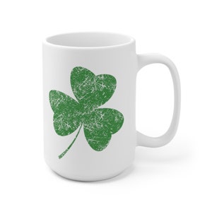 A 15-ounce white ceramic coffee mug featuring Sweet Holdings distressed, green shamrock, design, printed on both the front and back sides of the mug.