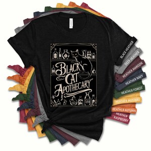 May include: Black t-shirt with a black cat and the text "Black Cat Apothecary" in a vintage style font. The design features a black cat sitting on a shelf with various bottles and jars. The t-shirt is available in a variety of colors, including black heather, deep heather, heather maroon, heather navy, heather forest, heather mustard, heather autumn, and heather raspberry.