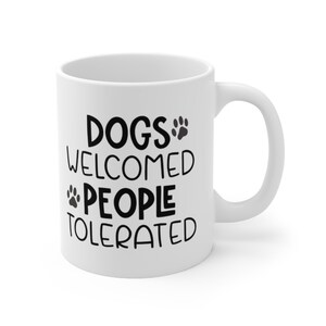 An 11-ounce white, ceramic, coffee cup featuring Sweet Holdings, Dog Welcomed People Tolerated, printed on both the front and back sides of the mug.