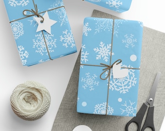 May include: Several wrapped gifts with light blue snowflake patterned paper, tied with twine and white tags. A spool of twine, scissors, and blank tags are also visible, suggesting gift wrapping supplies.