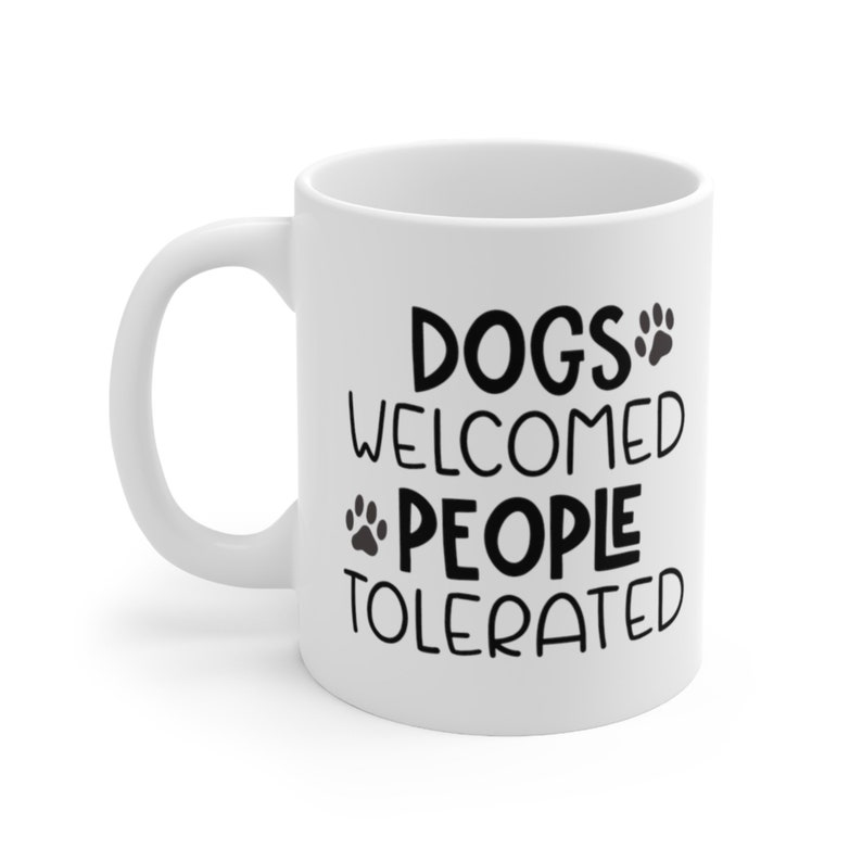 May include: White ceramic coffee mug with black text that reads "Dogs Welcomed People Tolerated" with a paw print graphic.